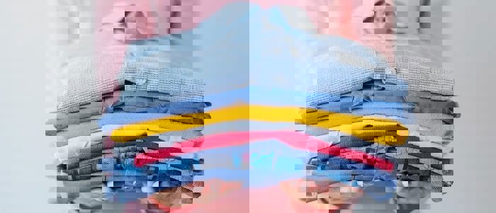 Girl Holding Pile Of Washed And Ironed Clothes Min